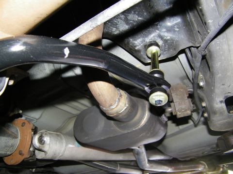 2003 Ford Crown Victoria - Close-up of an installed anti-roll bar end link and bracket beside the driveshaft on the undercarriage