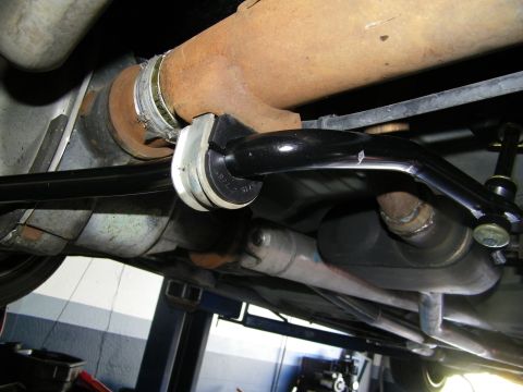 2003 Ford Crown Victoria - Anti-roll bar secured by a bushing clamp to the chassis with a surface-rusted exhaust pipe alongside