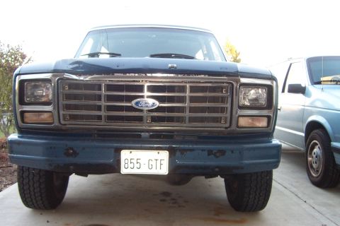 1980 Ford Bronco - Front view of a 1980 Ford Bronco, showing its grille and bumper. A second vehicle is visible to the right.