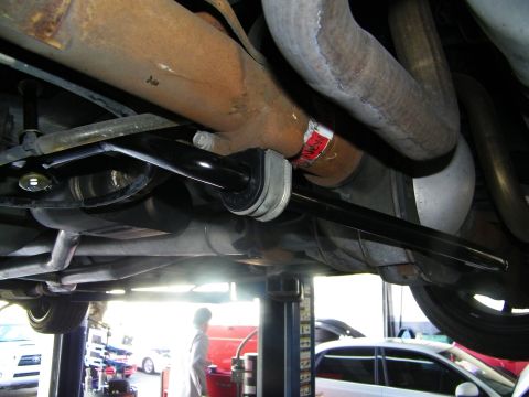 2003 Ford Crown Victoria - Anti-roll bar link with red-tagged hardware beside a surface-rusted exhaust under a raised vehicle