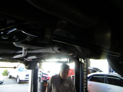 2003 Ford Crown Victoria - Underbody silhouette showing driveshaft and exhaust, worker and parked cars in bright background