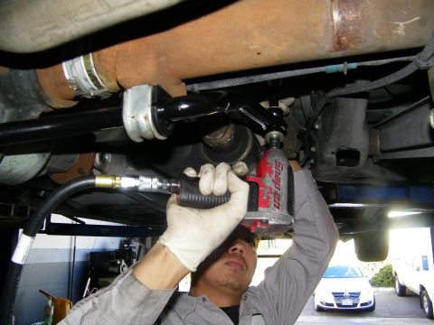 2003 Ford Crown Victoria - Gloved technician torquing an anti-roll bar fastener with a Snap-on impact gun beneath the chassis