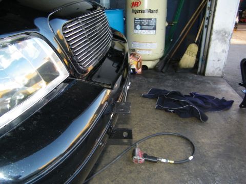 2003 Ford Crown Victoria - Low front view of black car with bracket and coiled air line near Ingersoll-Rand compressor