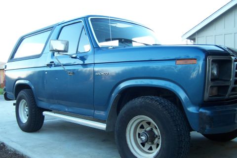 1980 Ford Bronco - A blue 1980 Ford Bronco is shown from a three-quarter front angle, parked on a concrete surface.