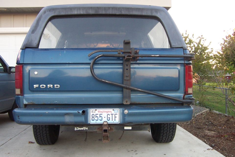 Rear of blue Ford Bronco with steel swing-out tire carrier and Washington 855-GTF plate