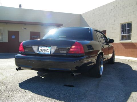 2003 Ford Crown Victoria - Lowered black Crown Victoria from behind showing Limited badge, dual tips and chrome-lip wheels.