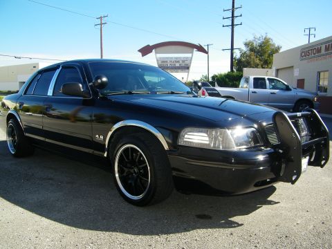 2003 Ford Crown Victoria - Front quarter of black Crown Victoria fitted with police-style push bumper and dark wheels.
