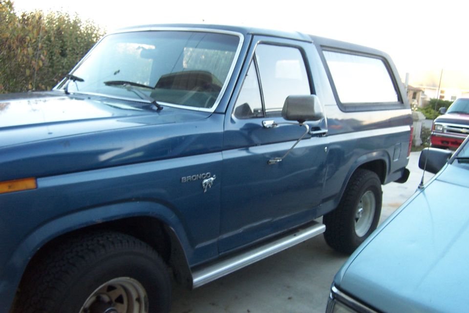 Blue full-size Ford Bronco side view with hardtop, side steps and BRONCO badge