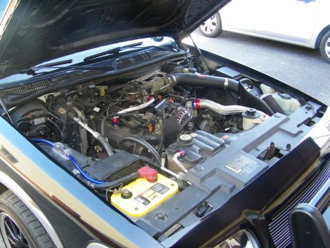2003 Ford Crown Victoria - Side angle of a modified V8 engine bay showing intake tube and battery hardware.