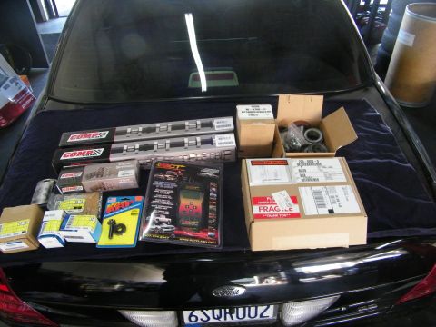 2003 Ford Crown Victoria - Auto parts spread across a black Ford trunk lid including COMP Cams and an SCT tuner.