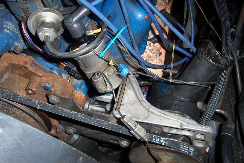 Close-up of engine distributor cap with blue spark plug wires and some zip ties