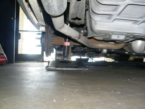 2003 Ford Crown Victoria - Undercarriage view with rear shock, exhaust and fuel tank over a shop alignment platform.