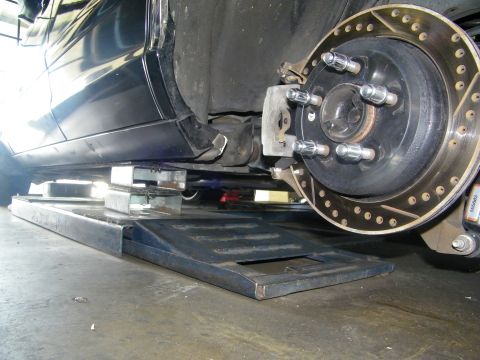 2003 Ford Crown Victoria - Detail of lug studs and a cross-drilled disc brake rotor on a lowered black vehicle.