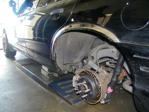 2003 Ford Crown Victoria - Side view of a lowered black car on a ramp with the rear wheel off, showing hub and rotor.