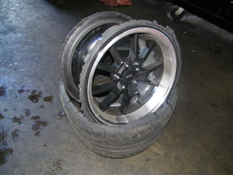 2003 Ford Crown Victoria - Pair of polished-lip SVT wheels with disintegrated tires stacked together on concrete.