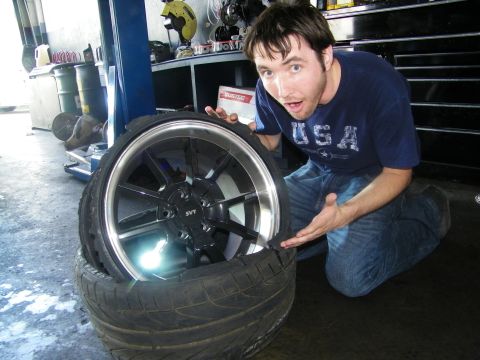 2003 Ford Crown Victoria - Workshop shot showing a polished-lip SVT alloy wheel with a man gesturing beside it