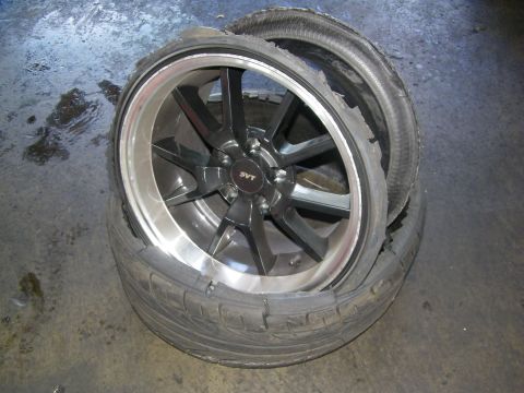 2003 Ford Crown Victoria - Polished-lip SVT alloy wheel fitted with a torn, delaminated tire resting on concrete
