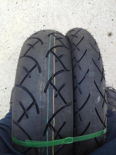 1995 Ford Bronco - A close-up view of two motorcycle tires, one slightly in front of the other, secured with a green strap.