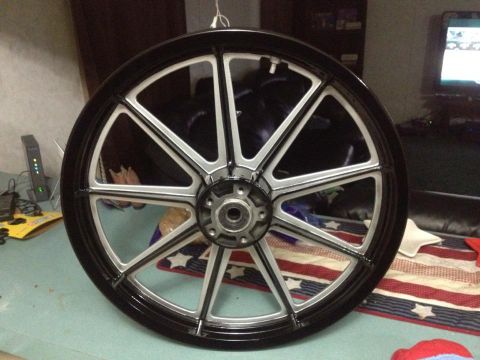 1995 Ford Bronco - A custom motorcycle wheel with a black rim and silver spokes is displayed indoors.