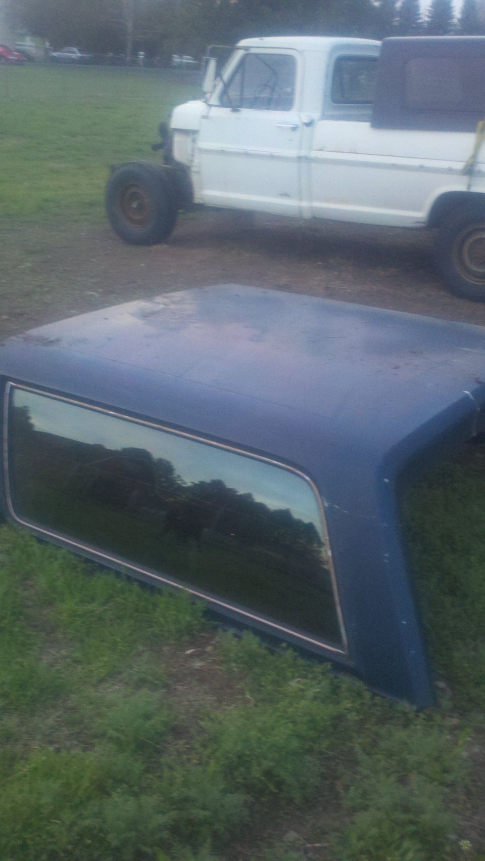 blue truck bed cap in foreground, white truck in background