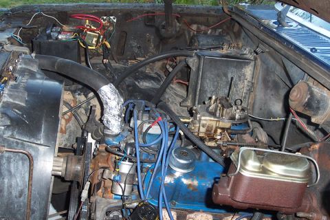 1980 Ford Bronco - Close-up view of a vehicle's engine bay, showing the carburetor, distributor, and spark plug wires.