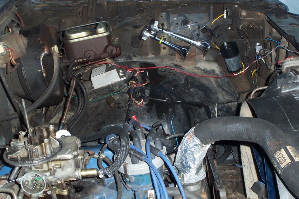 Engine bay with chrome triple air horns, compressor, carburetor and blue spark plug wires