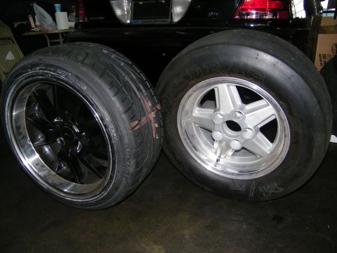 2003 Ford Crown Victoria - Side-by-side mounted tires showing a treaded tire and a bald slick on silver wheel
