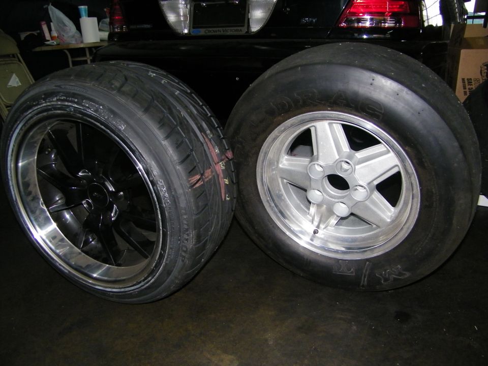 Black alloy wheel with grooved tire next to silver wheel with smooth slick tire