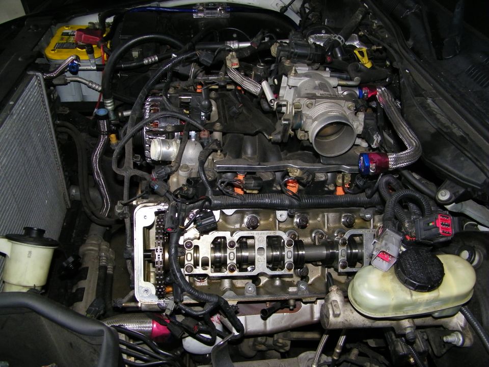 V8 engine bay with cylinder head removed showing valvetrain and throttle body