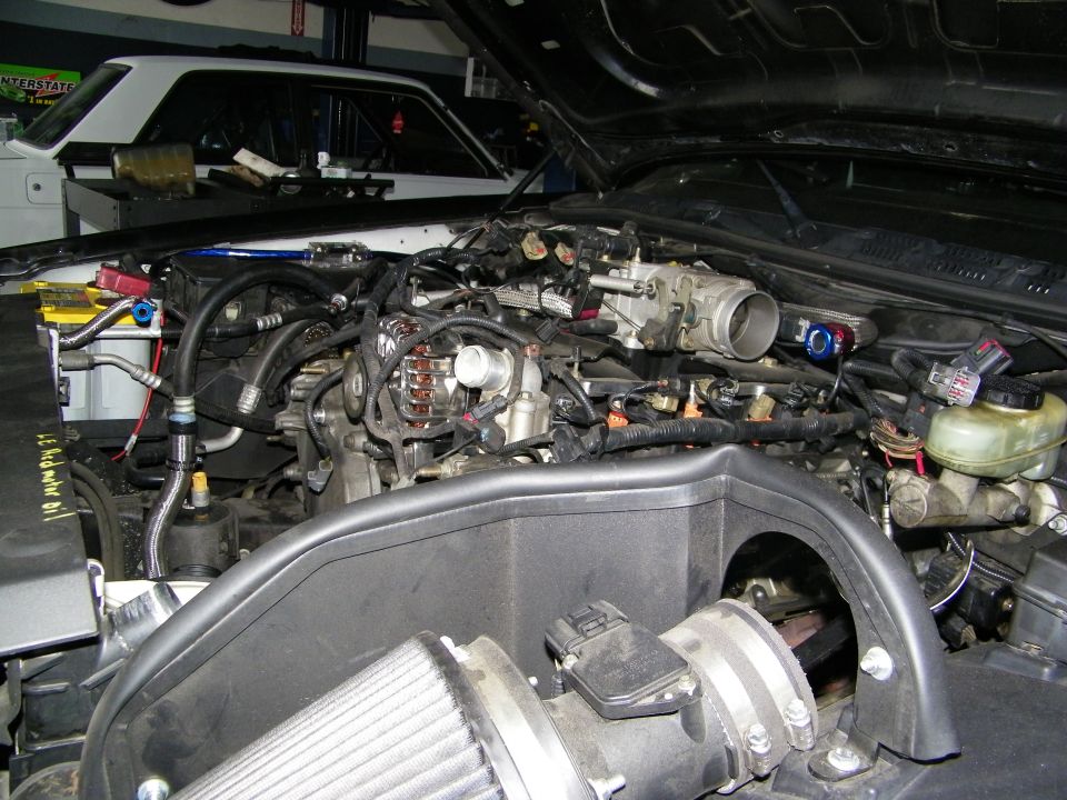 Engine bay teardown with cold-air intake and exposed engine block under raised hood