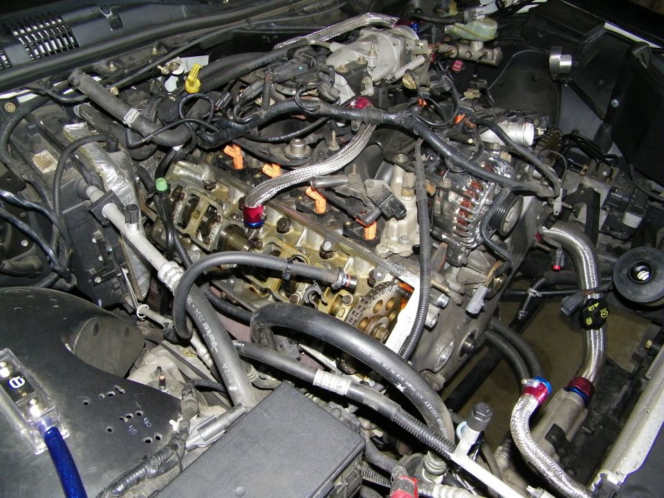 Engine bay with exposed cylinder head valvetrain and wiring during rebuild