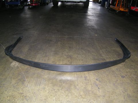 2003 Ford Crown Victoria - Curved black front spoiler air dam laid out on shop floor with vehicles behind