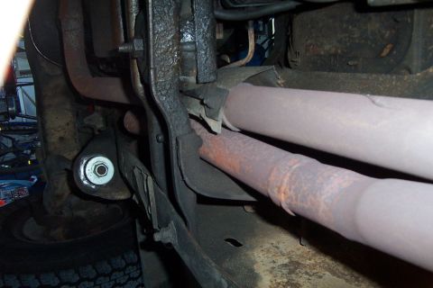 1980 Ford Bronco - Close-up view of the exhaust system and suspension parts underneath a vehicle.
