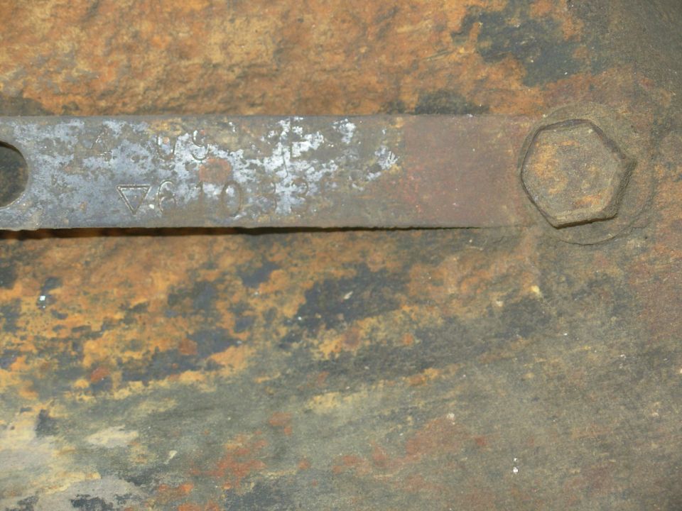 Rusty stamped metal arm with forged markings