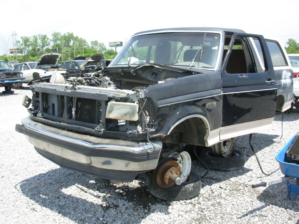 Black and tan Ford Bronco SUV stripped in a junkyard