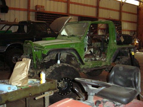 1992 Ford Bronco - A green off-road vehicle is in a garage next to a black truck.