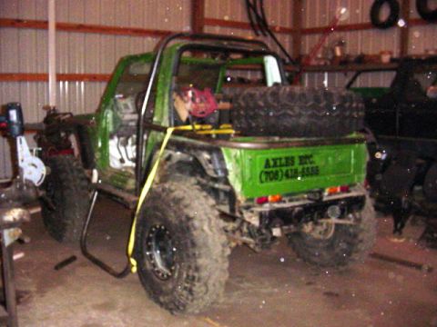 1992 Ford Bronco - Off-road vehicle with custom roll cage and spare tire in a garage setting.