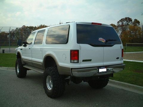 2000 Ford Excursion - Rear view of a white 2000 Ford Excursion SUV modified with a lift kit and large off-road tires.