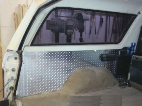 1986 Ford Bronco - Diamond plate paneling installed on the interior wall of a vehicle's rear cargo area.