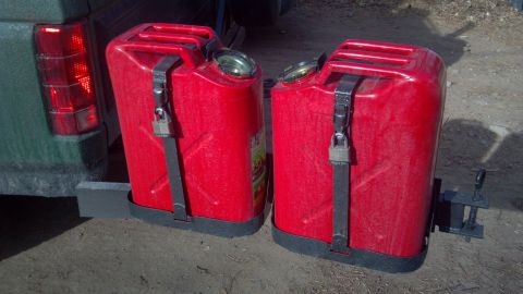 1986 Ford Bronco - Two red jerry cans are mounted on the rear bumper of a vehicle.