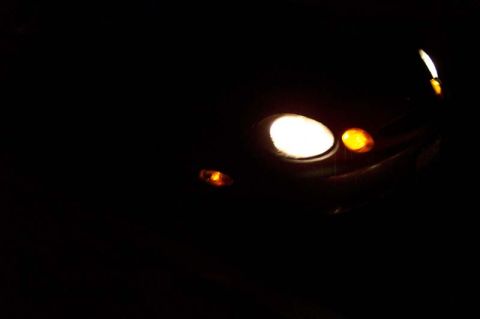 1996 Ford Taurus - Headlights and turn signals are visible on the front of a dark vehicle.