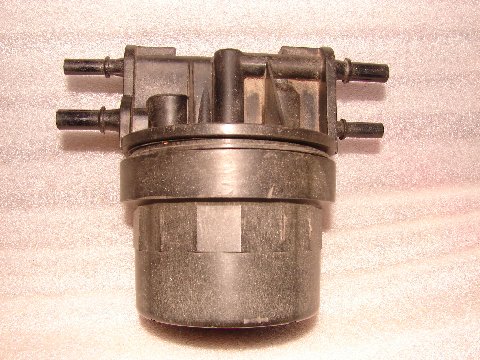 1973 Ford Ranchero - A black plastic fuel filter with multiple hose connections is shown against a textured background.