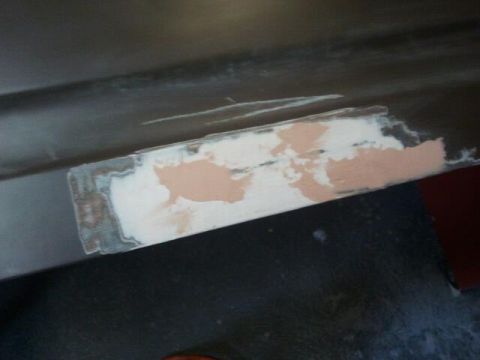1979 Ford Bronco - Body filler is being applied to a section of a car panel during repair.