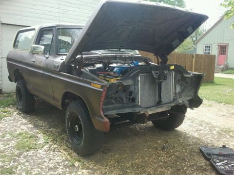 1979 Ford Bronco - This 1978 Ford Bronco is missing its front grille and bumper, with the hood open revealing the engine bay.