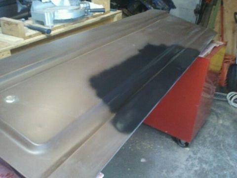 1979 Ford Bronco - Car door panel with a patch of primer applied, resting on a red cabinet.