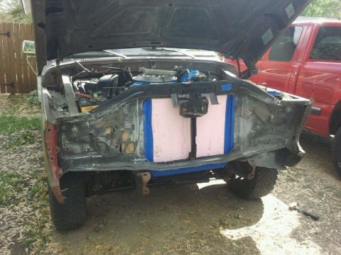 1979 Ford Bronco - The front end of a vehicle is disassembled, showing the engine and radiator area, with another truck visible in the background.
