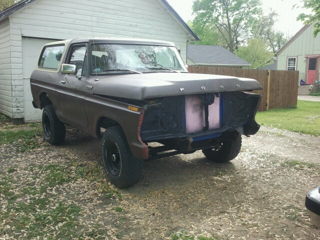 Brown Ford Bronco with missing front grille and bumper, parked in a driveway