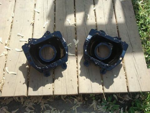 1979 Ford Bronco - Two black headlight buckets are laid out on a wooden surface, possibly for restoration or replacement.