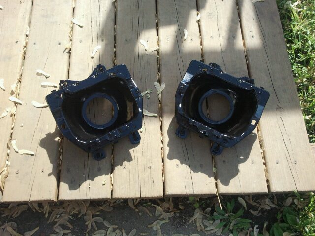 Pair of black headlight buckets sitting on wooden planks