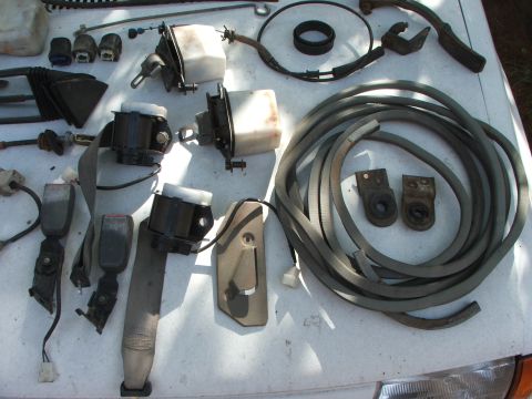 1991 Ford Festiva - Collection of automotive parts, possibly for a 1991 Ford Festiva, including seatbelts and hoses.